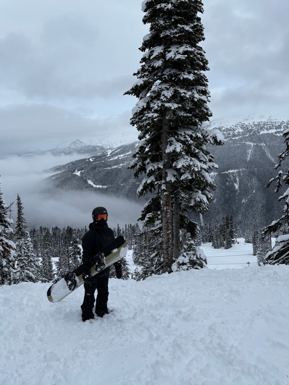 Sahir Sood holding a snowboard at Whistler on a snowy mountain day